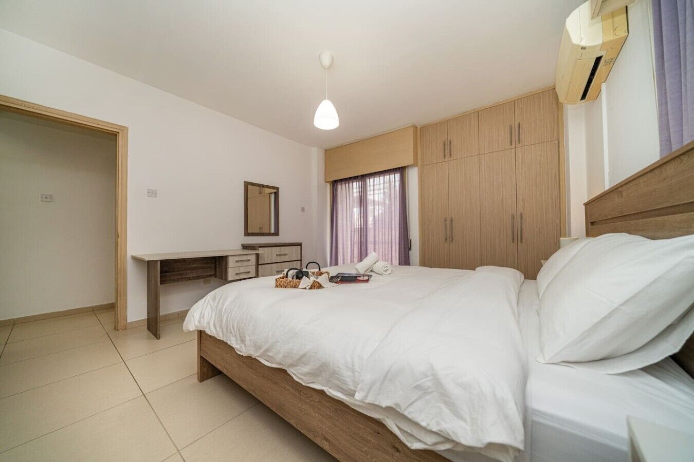 Une chambre à coucher avec un lit, un bureau, une armoire et un miroir.