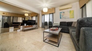 A modern living room with a flat-screen TV, a sofa, a coffee table, and a large mirror. - 3 bedroom flat near center (Nicosia)