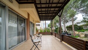 A covered balcony with a table and chairs, a car parked outside, and a view of trees and a building. - 3 bedroom flat near center (Nicosia)