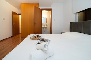 Une chambre d’hôtel avec un lit, une armoire en bois, une salle de bain avec un lavabo et une fenêtre.