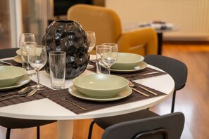 A dining table set with plates, glasses, and cutlery, surrounded by chairs. - 2 bedroom flat in center (Nicosia)