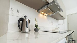 A modern kitchen with a stainless steel kettle, a small potted plant, and a built-in range hood. - 1 Bedroom flat in Aglatzia (Aglantzia)