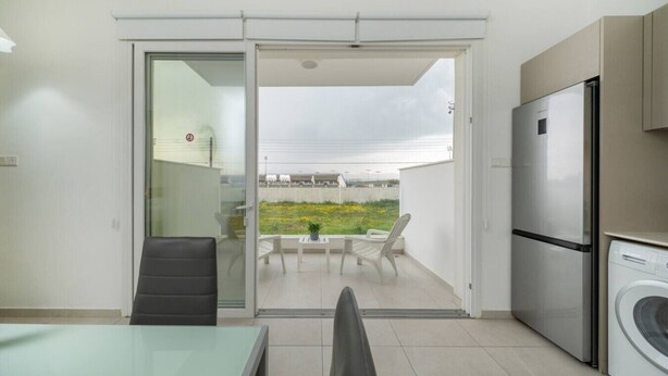 A modern kitchen with a refrigerator, washing machine, and a dining area with a table and chairs. - 1 Bedroom flat in Aglatzia (Aglantzia)