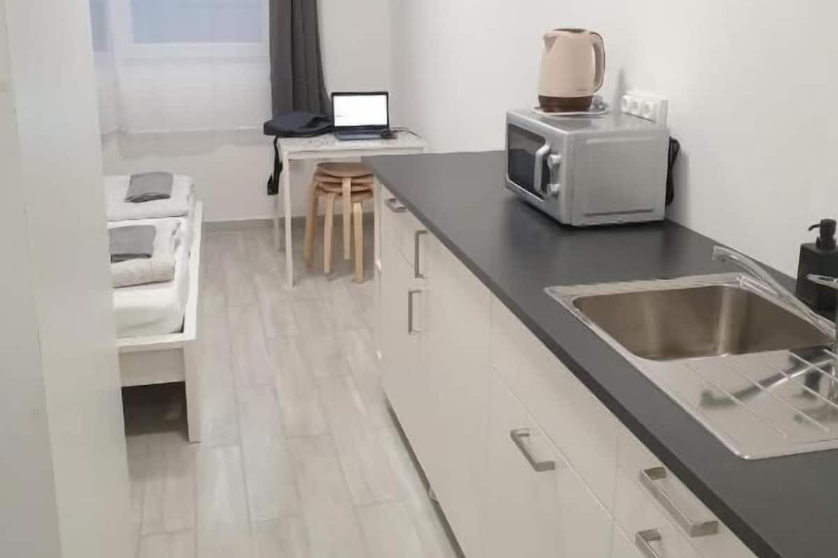 Een kleine keuken met een zwart aanrecht, een roestvrijstalen spoelbak en een magnetron.