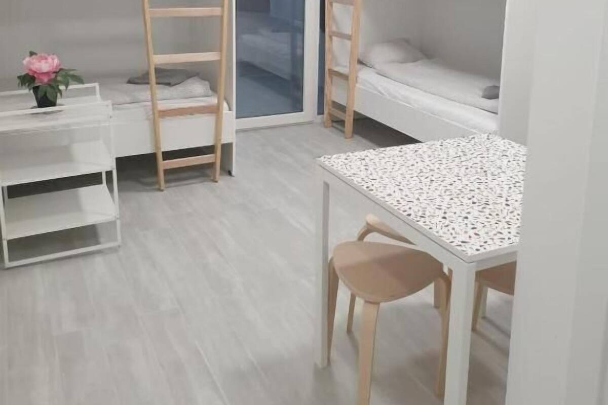 Een kleine kamer met stapelbedden, een bureau en een stoel.