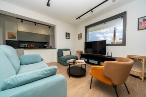 A modern living room with a sofa, armchair, coffee table, and a TV.