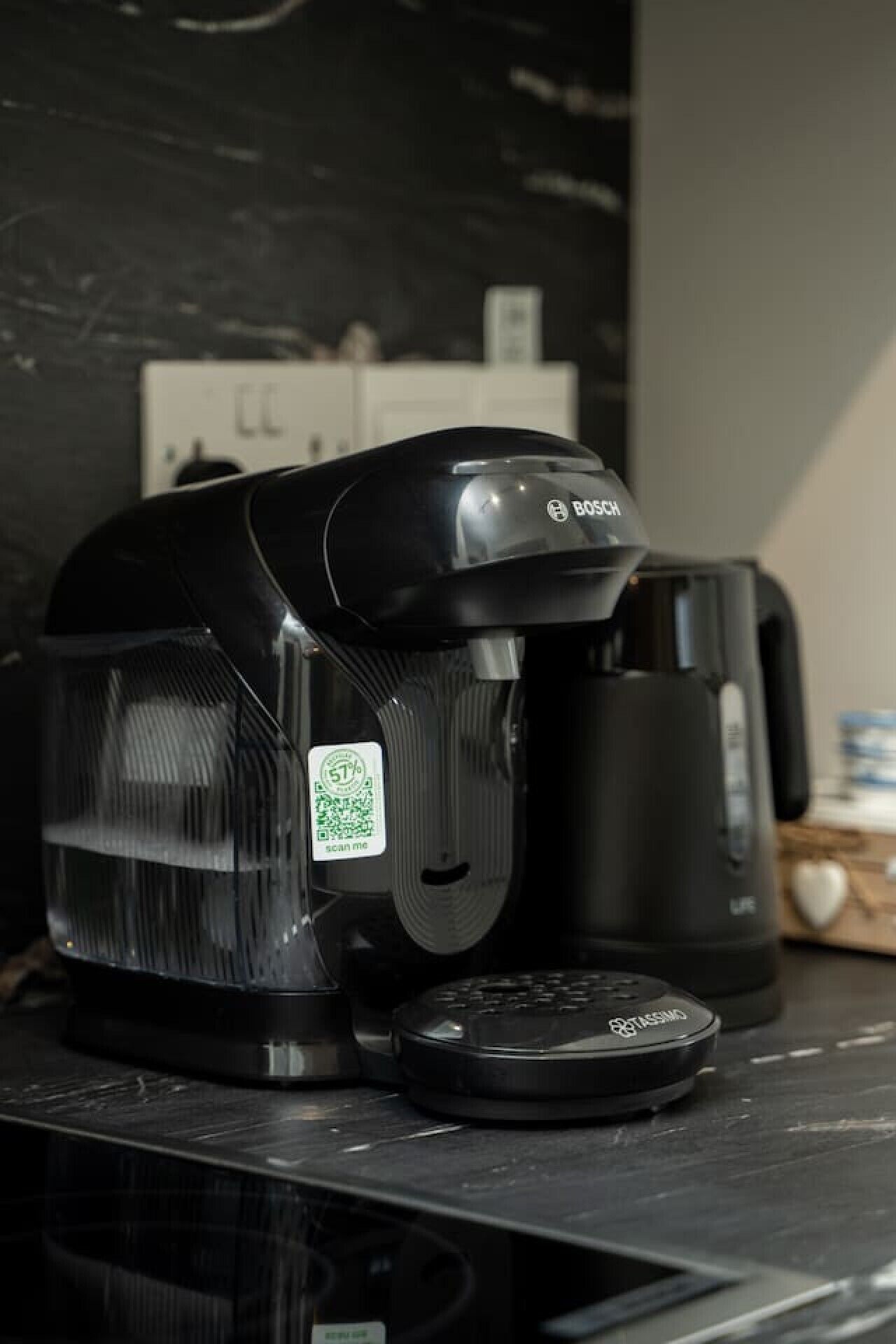 Une machine à café avec un code QR sur le côté, posée sur un plan de travail.