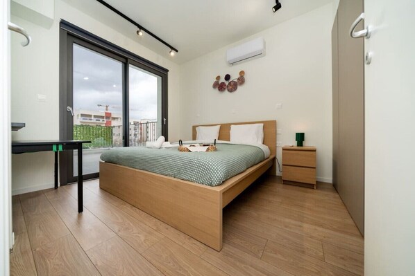 A bedroom with a bed, bedside table, and a desk with a chair.