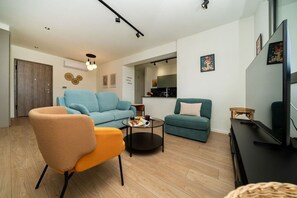 Ein modernes Wohnzimmer mit einer Couch, einem Sessel, einem Couchtisch und einem Fernseher.