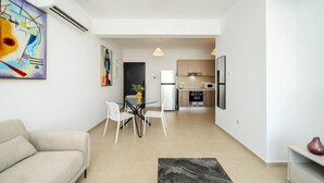 Un salon moderne avec un canapé, une table à manger et des chaises, une cuisine en arrière-plan et un tapis en marbre.