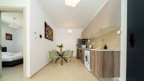 A compact living space with a kitchenette, a dining area, and a bedroom.