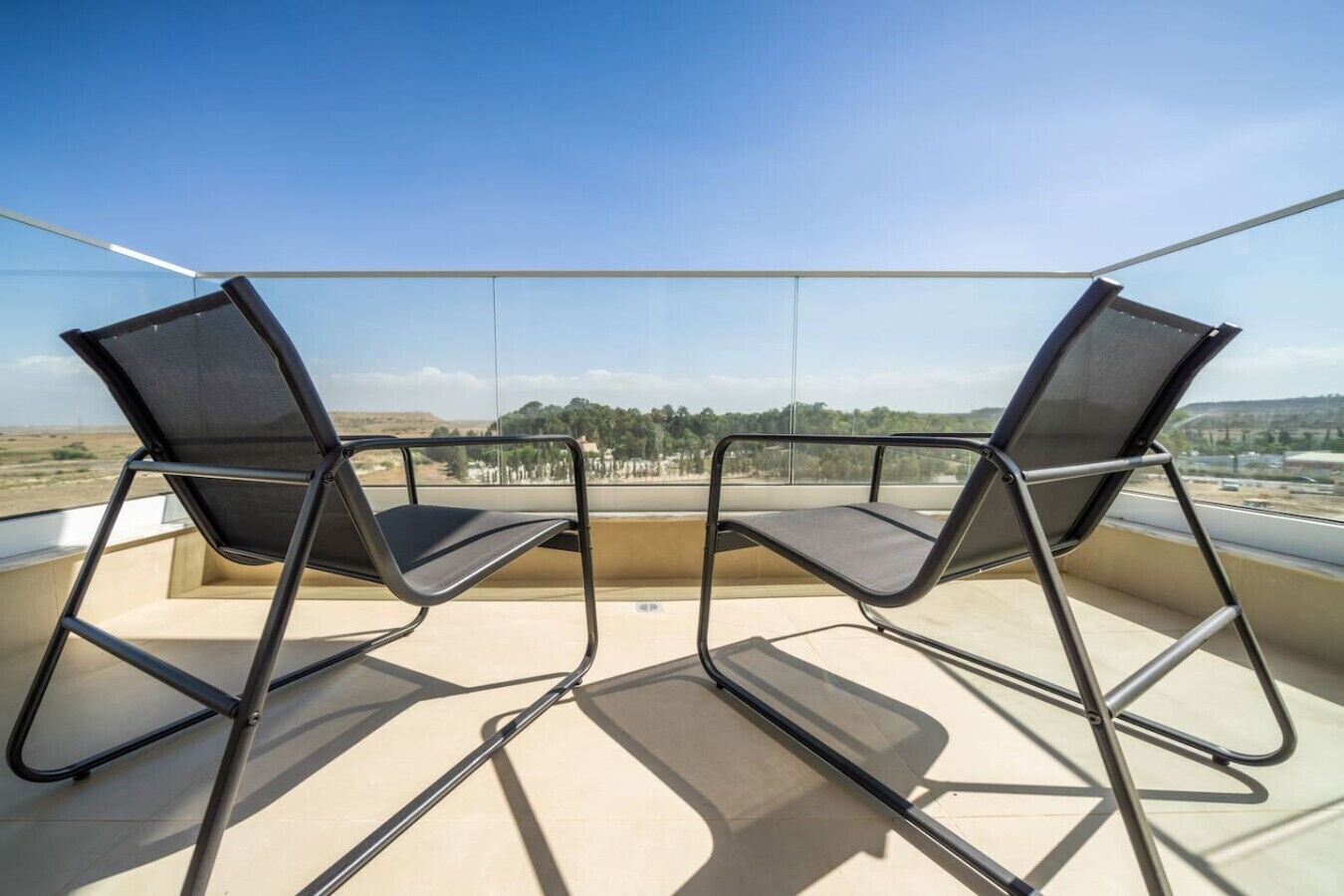 Two chairs on a balcony with a clear view of the landscape.