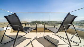 Two chairs on a balcony with a clear view of the landscape.