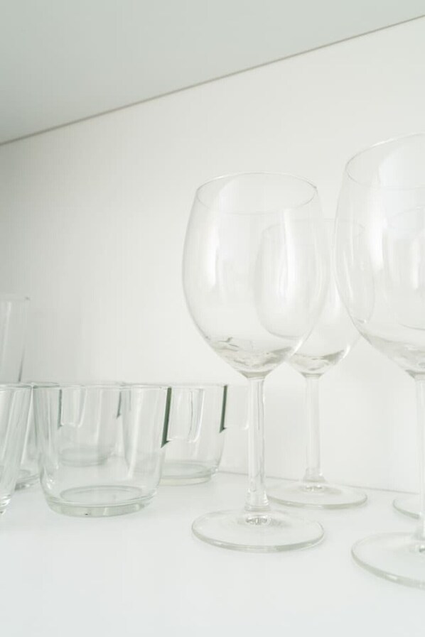 A row of clear glass wine glasses on a white surface.
