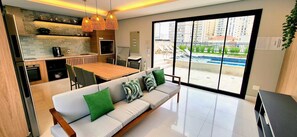 A modern kitchen with a dining area, large windows, and a view of a swimming pool.