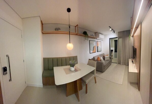 A modern living room with a dining area, a built-in bench, and a flat-screen TV.
