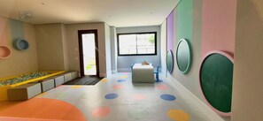 A children's play area with colorful circular patterns on the floor, a bench, and a table with toys.