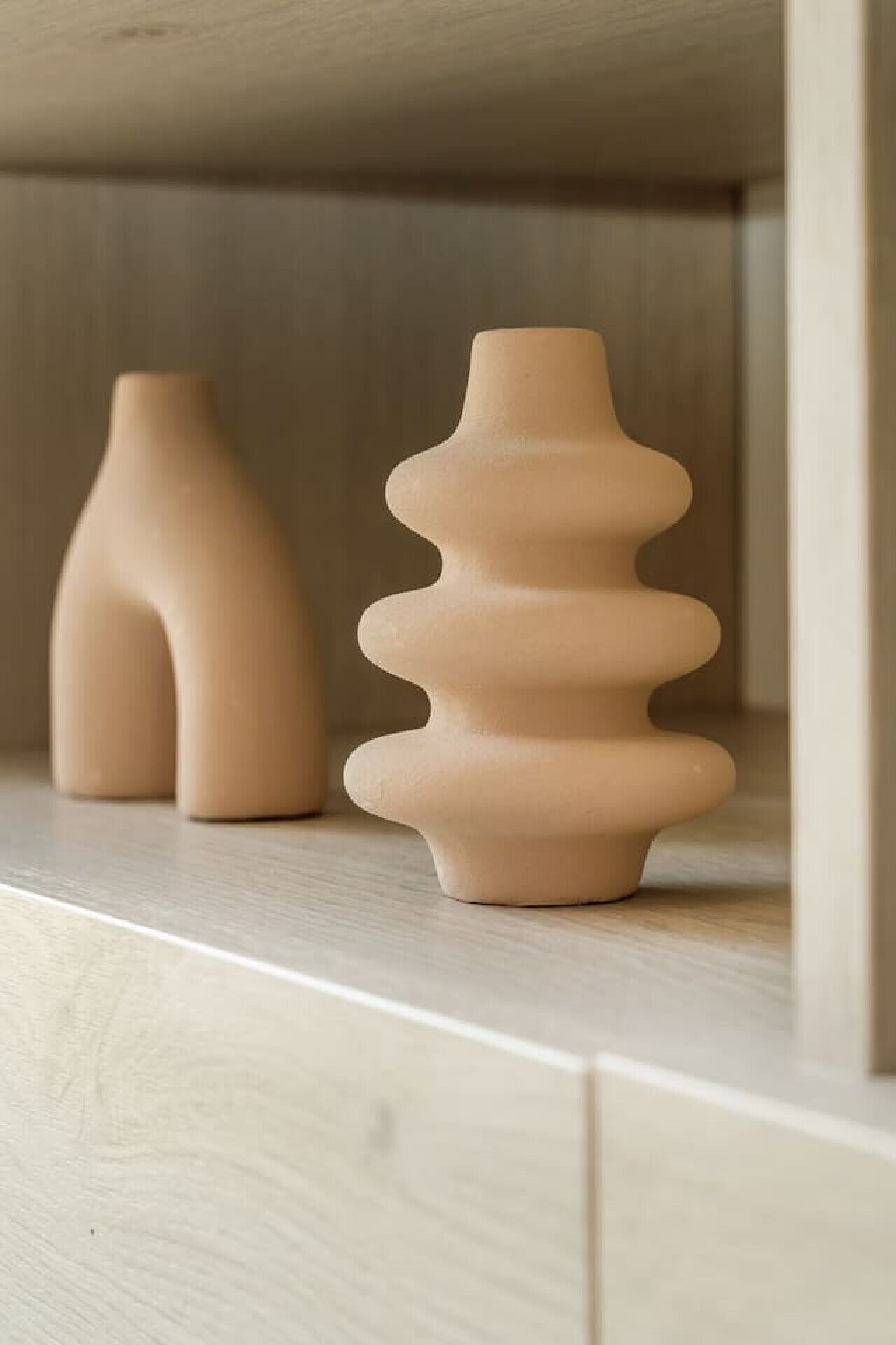 Deux vases en céramique sur une étagère en bois.