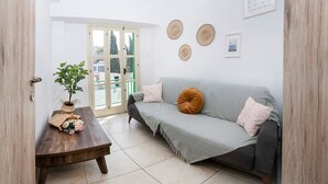 Uma sala de estar com um sofá cinza, uma mesa de centro de madeira e um vaso de plantas.