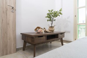 Ein Nachttisch aus Holz mit einer Topfpflanze und Dekoration, eine Holztür und ein Fliesenboden.