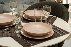 Una mesa de comedor preparada con platos, vasos y cubiertos.