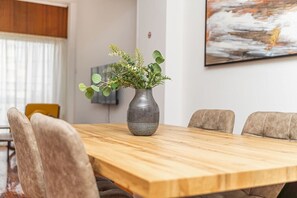 Uma mesa de jantar com um vaso de plantas verdes, rodeada por cadeiras.