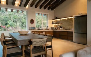 A modern kitchen with a large island, wooden dining table, and chairs. - Lujoso Penthouse frente al mar - Piscina privada (Puerto Vallarta)