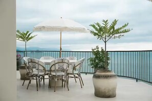 A balcony with a table and chairs, a white umbrella, and a potted plant. - Lujoso Penthouse frente al mar - Piscina privada (Puerto Vallarta)