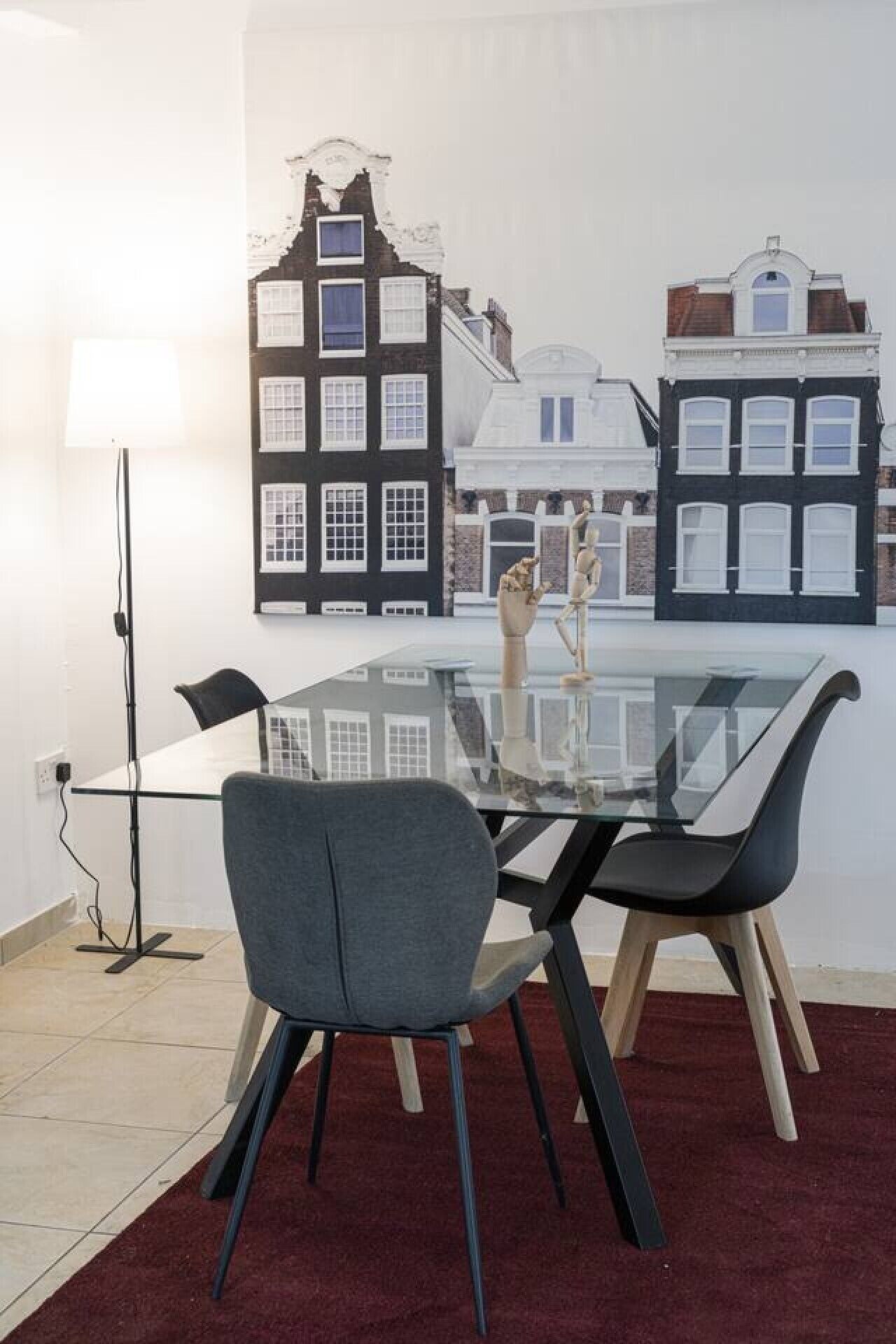 Et moderne spiseområde med et glasbord, to stole og en lampe.