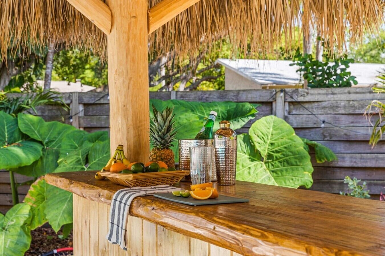 A wooden bar with a thatched roof, a pineapple, and a bottle of green liquid.