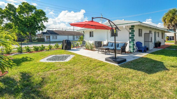 A house with a patio, outdoor furniture, and a red umbrella. - 3BR 2BA with Modern Interior & Backyard (Oakland Park)