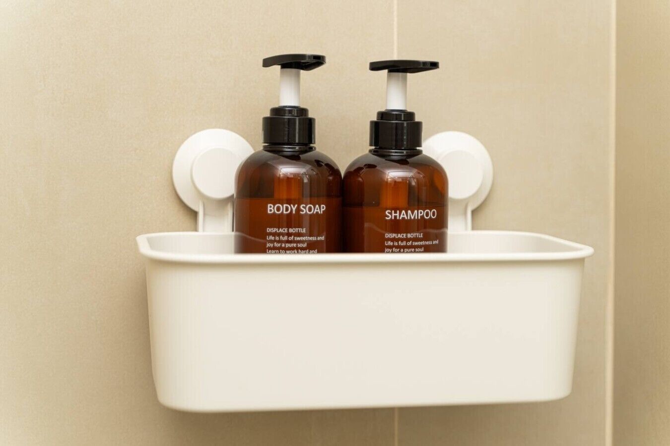 Due flaconi di sapone corpo e shampoo su uno scaffale bianco in bagno.