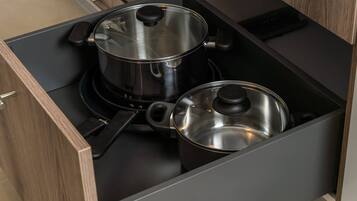 A kitchen drawer with two stainless steel pots.