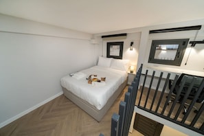 Un dormitorio con cama, mesita de noche, lámpara y ventana.