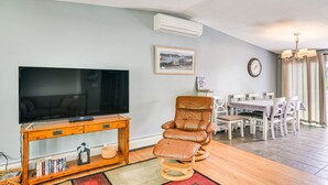 Un salon comprenant un téléviseur, un fauteuil en cuir, une table à manger et des chaises.