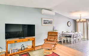 Una sala de estar con televisión, sillón de cuero, mesa de comedor y sillas.