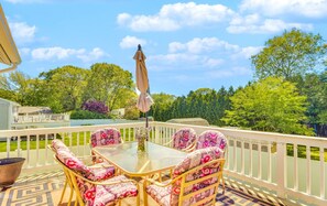 Ein Balkon mit Tisch und Stühlen, Blick auf einen See und eine weiße Umzäunung.