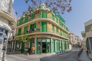A multi-story building with green shutters, a visible storefront, and a bicycle parked outside. - 2 bedroom flat in center (Nicosia)