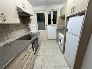 A compact kitchen with a stove, oven, washing machine, and refrigerator. - 2 bedroom flat in center (Nicosia)