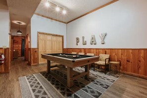 Ein Billardtisch in einem Raum mit Holzwänden und einem Schild mit der Aufschrift 'PLAY'.