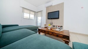 Ein modernes Wohnzimmer mit einer Couch, einem Holztisch und einem an der Wand befestigten Flachbildfernseher.