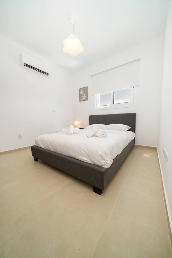 Un dormitorio moderno con una cama, mesitas de noche y una lámpara en el techo.