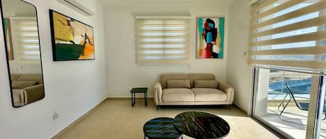 Uma sala de estar moderna com um sofá, duas mesas redondas e obras de arte nas paredes.