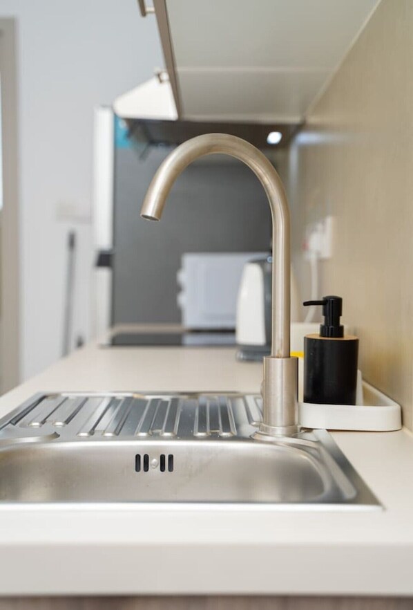 A modern kitchen with a stainless steel sink, a faucet, and a soap dispenser.