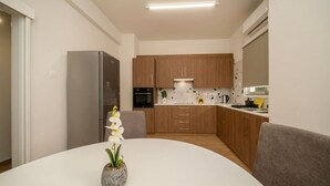 Una cuina moderna amb armaris de fusta, un forn de sobre i una taula de dinar blanca amb una orquídia en test.