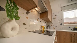 Una cocina con encimera blanca, estufa, ventana y una planta.