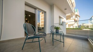 Un balcó amb dues cadires, una d'elles amb una planta, i una porta corredissa de vidre que dona a un espai interior.