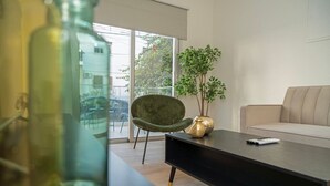 Una sala de estar moderna con un sofá, un sillón verde, una mesa de centro y una planta en maceta.
