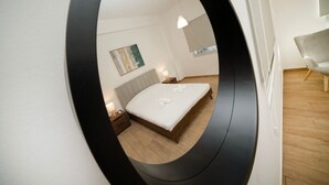 Un dormitorio con cama, mesita de noche, lámpara y un cuadro en la pared.