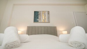 Habitació d'hotel amb un llit, dues làmpades de nit, un quadre a la paret i dues tovalloles enrere.